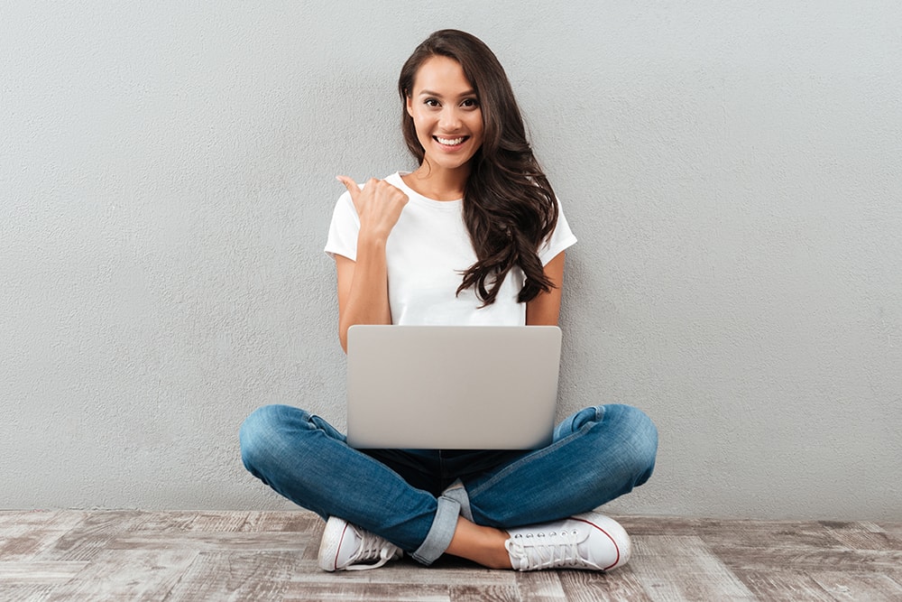 women with laptop pointing with thumb